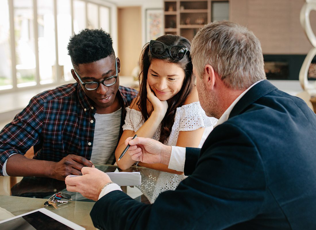 About Our Agency - Insurance Agent Sits With a Couple to Review Their Policy at an Office