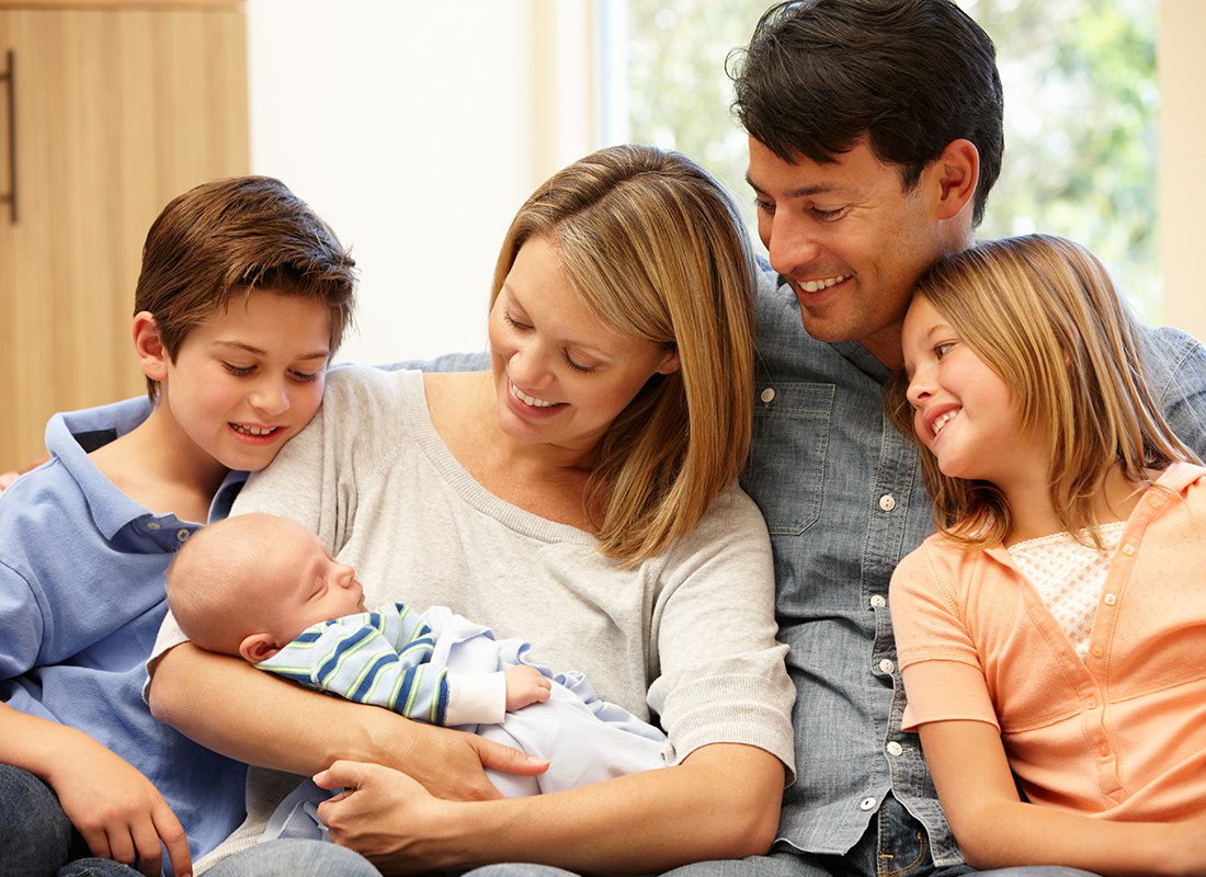 Personal Insurance - Happy Family and Two Young Children Welcome Their New Baby to the Family at Home
